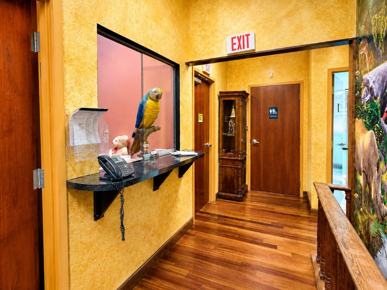 The check-in reception window with a jungle-themed hallway and safari mural